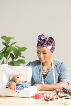 Woman pushing fabric through sowing machine