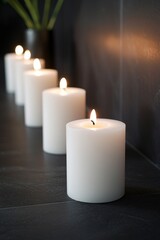 A row of white candles in a dark room, all but one unlit, creating a striking contrast. 