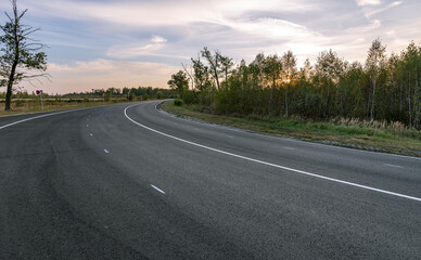 A long, empty road with a few trees in the background