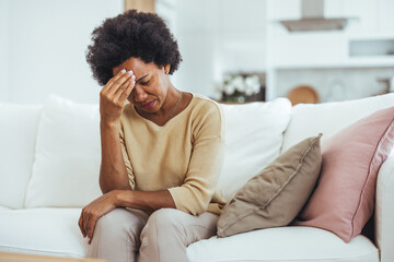 Worried Woman Sitting on Couch Holding Her Head