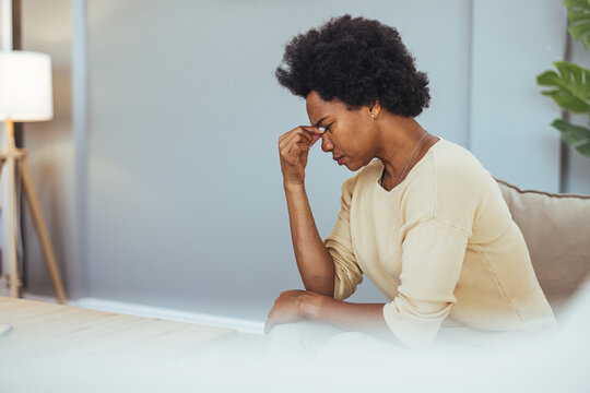 Stressed Woman Sitting on Sofa Holding Her Head