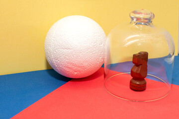Still life with a plastic foam ball and wooden chess knight under glass bell	