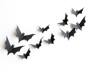 Fototapeta premium Group of black paper bats flying in formation, isolated on white background, symbolizing Halloween celebration and decoration.