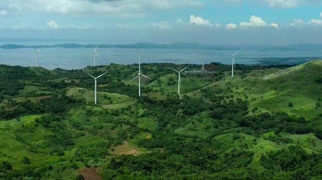 Wind farm on green island of Rizal, Pililla in Philippines. Renewable and sustainable energy theme in Asia. Aerial wide shot.