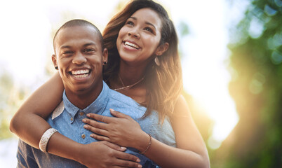 Obraz premium Happy couple, love and nature with hug for piggyback, holiday or bonding weekend together. Young, man and woman with smile in joy, relationship or date for freedom, care or support at outdoor park