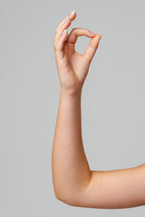 A hand gesturing the OK sign against a simple grey background