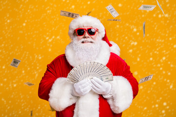 Portrait of his he nice attractive cheerful cheery fat overweight Santa holding in hand throwing waste usd 100 fan cash salary deposit isolated bright vivid shine vibrant yellow color background