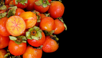 Wet persimmon fruits isolated on black background. Copy space for text.	