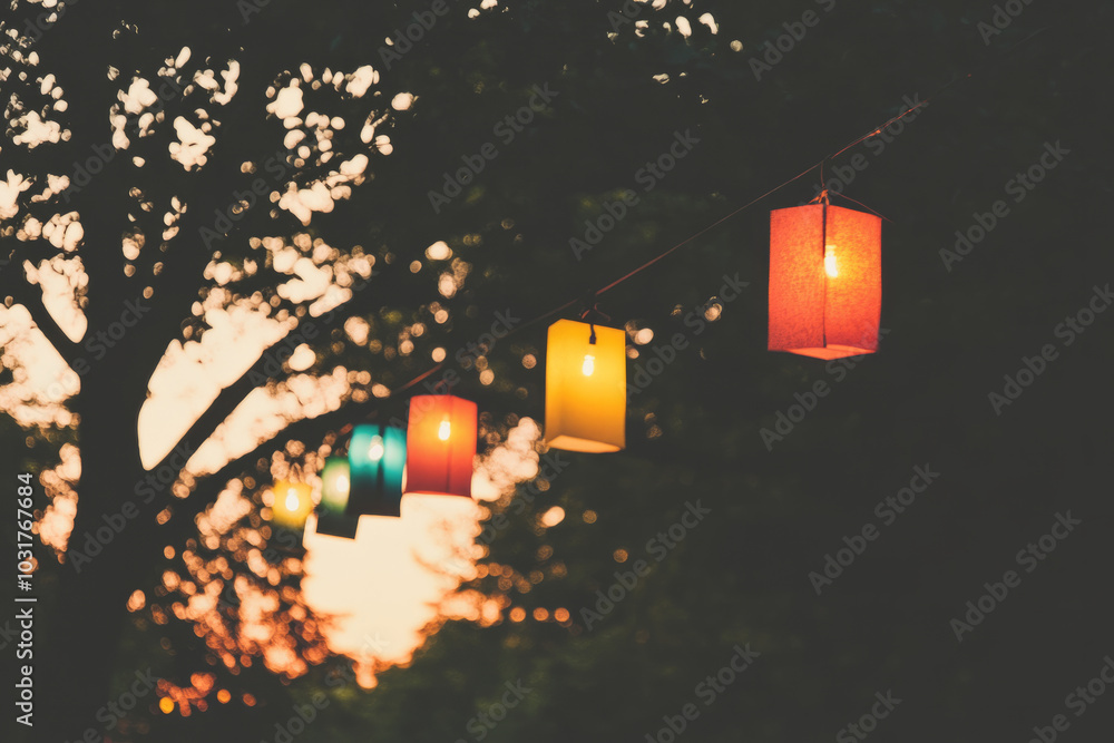 Poster A row of colorful lanterns hanging from a tree at dusk