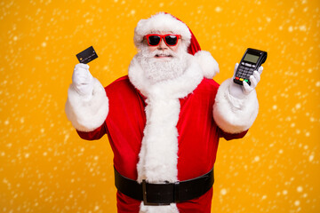 Portrait of his he nice attractive cheerful fat Santa holding in hand bank card digital terminal...