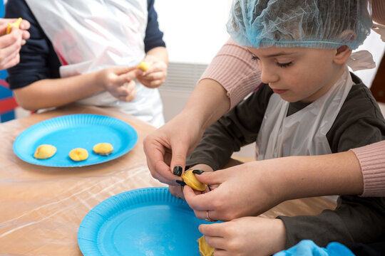 A dumpling-making workshop for a 7-year-old child. Hands-on learning experience where the child shapes dough and fills dumplings, capturing the joy of cooking and creative play