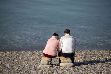 Two people sitting on a bench by the water