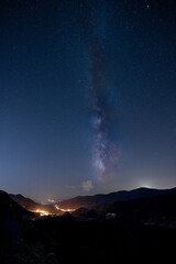 The Milky Way above the lights of a town in a valley