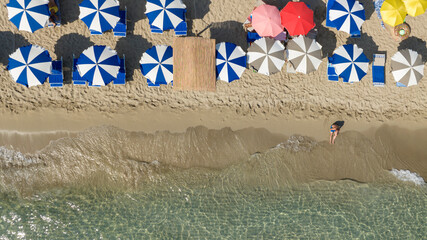 Perpendicular aerial view of many colorful umbrellas on a public beach in Salento, Puglia, Italy. Holiday concept.