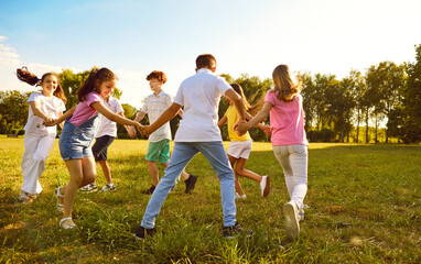 Group of a kids friends playing outside in the park standing in a circle and holding hands. Happy...