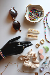 Hand figurine, sunglasses, gold jewelry, colorful bead jewelry, statement rings and various hair...