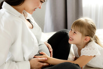 Midsection portrait of happy, beautiful, young careless pregnant woman, mother with cute little...