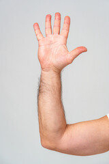 Hand raised in greeting against a plain background