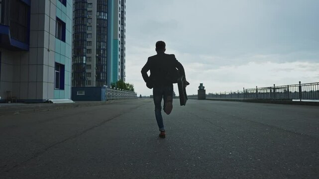 A man runs down an empty street in a city under overcast skies
