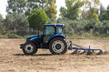 A tractor starts to pilow a crop field to prepare seeding winter wheat in autumn