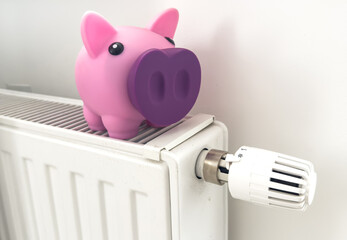 Radiator at home, the concept of rising heating prices. Piggy bank with a scarf sits on a radiator
