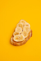 Tartine à la banane sur fond jaune, studio.