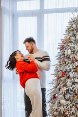 lovely couple dancing in front of christmas tree