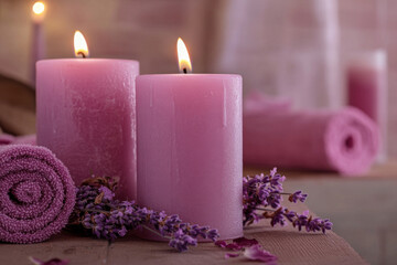 Pink Candles with Burning Flames and lavender Flowers on a Towel. Relaxing Spa and Wellness Aromatherapy