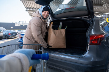 Man Loading Groceries into Car Trunk