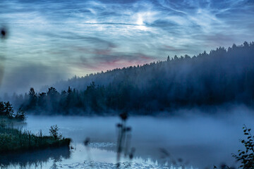 A foggy, light July night with silvery clouds on the Tura River, in the village of Mostovaya, near...