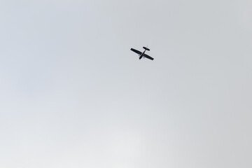 A small airplane flying overhead against a cloudy sky, viewed from below