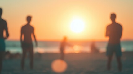 Blurred silhouettes of people enjoying a warm sunset on the beach, creating a dreamy, atmospheric scene filled with soft orange light.