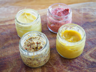 Closeup view of mustard jars on  wooden background