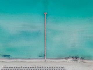 Aerial drone view of wooden pier and turquoise waters at Playa de Muro, Alcudia, Mallorca
