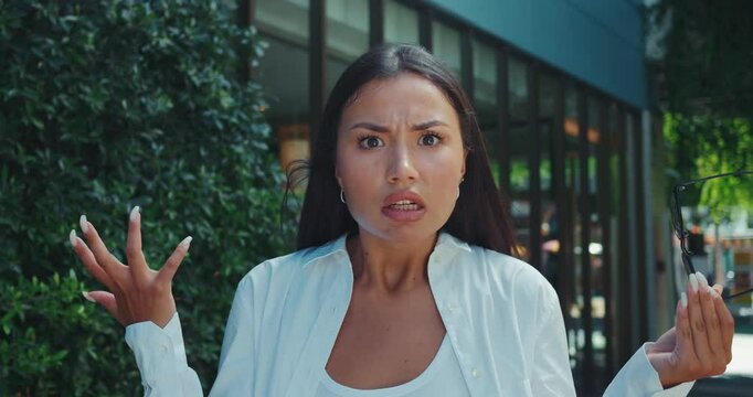 Young adult woman visibly taken aback removes glasses face full of shock and frustration. With wide eyes and disbelieving expression woman takes off her glasses comprehend shocking moment.