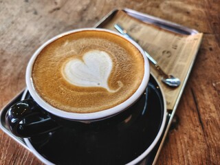 Heart coffee latte art milk foam on wood table background