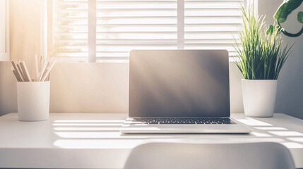 Obraz premium Simple, minimalist desk setup with a slim laptop, white chair, and sunlight streaming through nearby windows onto a clean surface