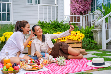 Two women are having picnic in garden.