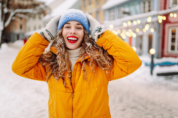 Young woman tourist walks along winter streets decorated with luminous garlands. Winter holidays. Christmas fair.