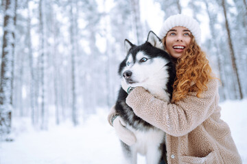 Cheerful woman in the snow playing with a husky dog. Friendship. Domestic dog concept.