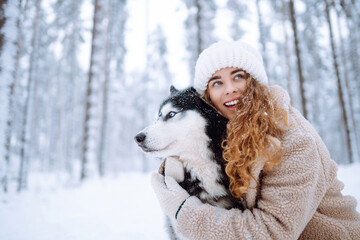 Cheerful woman in the snow playing with a husky dog. Friendship. Domestic dog concept.