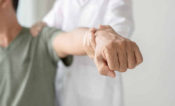 Female physiotherapists provide physical assistance to male patients with shoulder injuries massaging their shoulders for muscle recovery in the rehabilitation center. Physiotherapy concepts