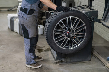 Obraz premium Mechanic balancing a wheel in a workshop. 