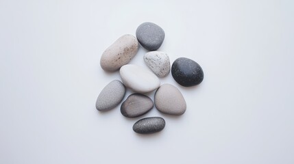 A small cluster of smooth river stones in varying shades of gray, arranged harmoniously on a white surface