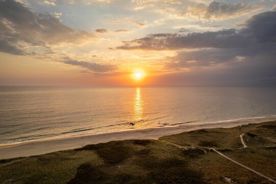 Serene beach sunset with golden hues reflecting on the ocean. Martha's Vineyard