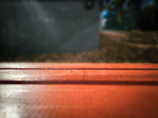 A red bench with a white tarp on it. The bench is in front of a wall