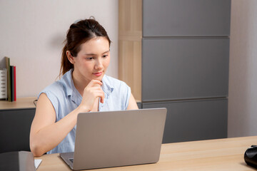Young caucasian business woman working with laptop while thinking for planning financial on desk in modern home office, businesswoman planning and thoughtful about working, business concept.