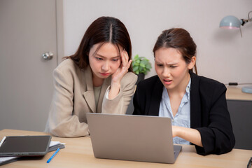 Two businesswoman stress and frustrated while working on laptop computer in office, two business woman serious and problem about project, expression and trouble, business and finance with problem.