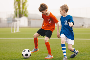Football soccer match for children. Boys in blue and red shirts playing football game on school...