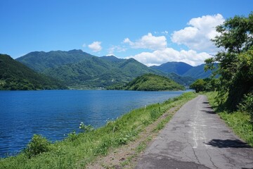 Tranquil lakeside path winding through lush mountains on a bright sunny day